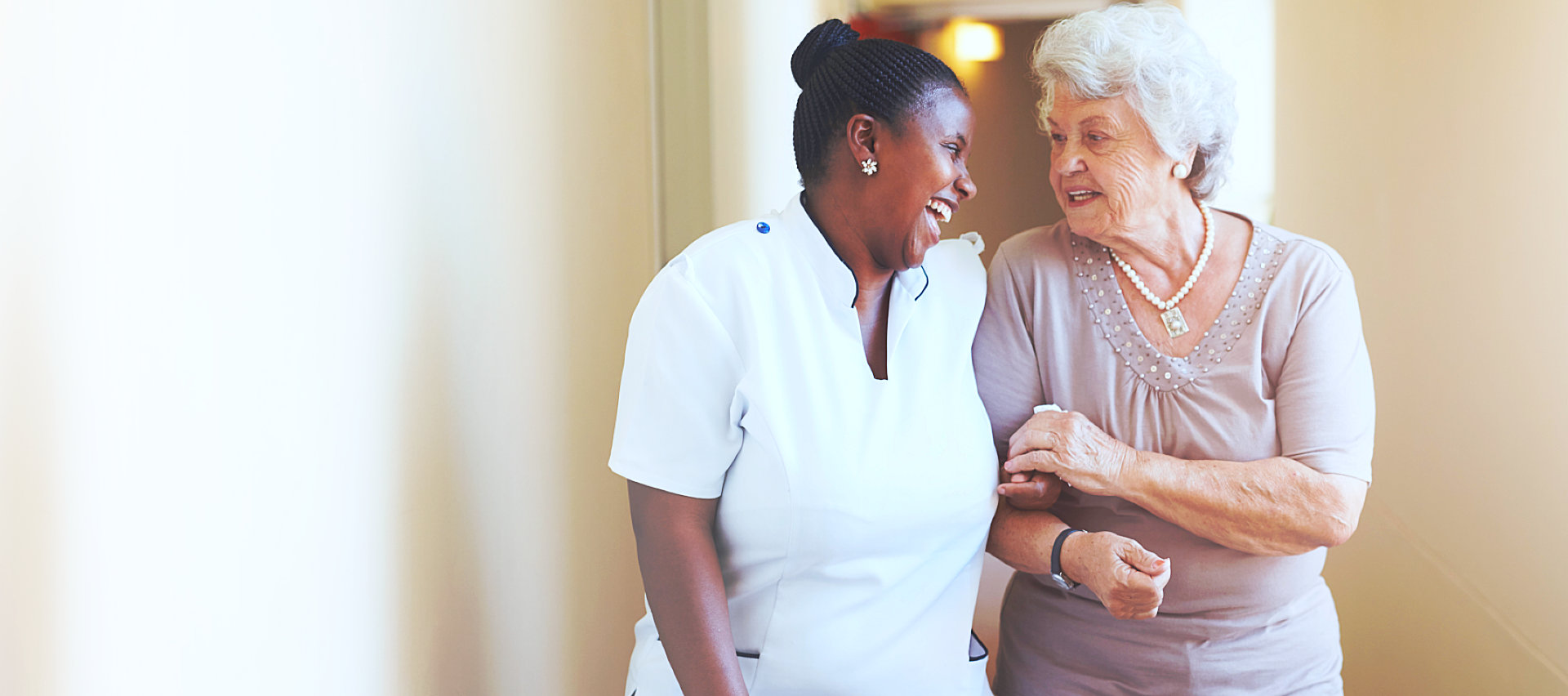 an elderly woman and a caregiver talking while walking