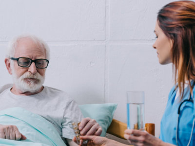 caregiver giving elder woman his medicine